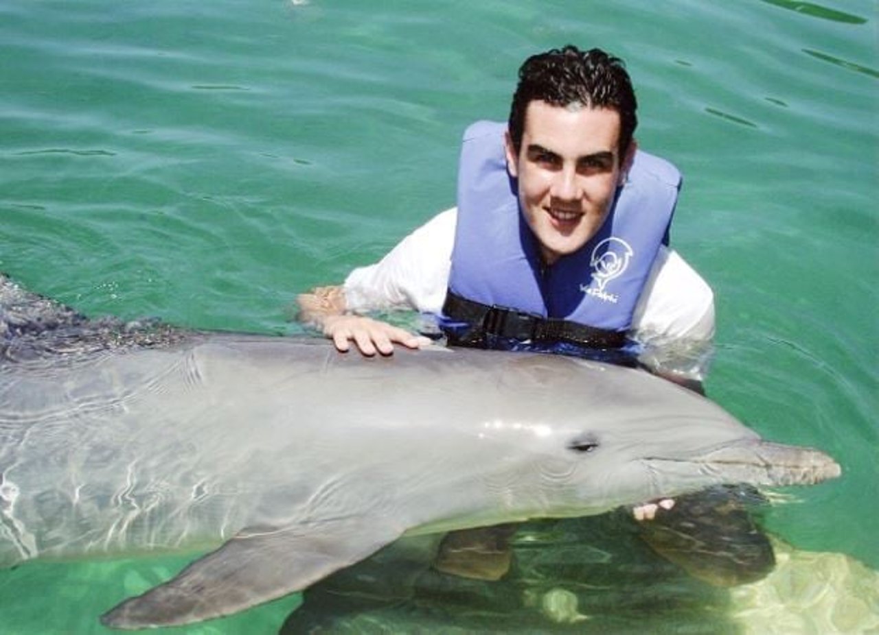  Ben Williamson on a boat with dolphin in background - World Animal Protection