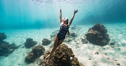 Woman swimming in OceanPositive suits made from ECONYL®, a fabric made from recycled plastic fishing gear.